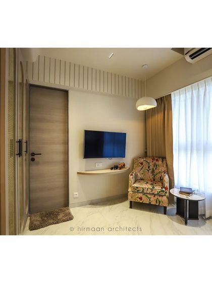 A full view of the guest bedroom, showing the comfortable armchair, floating TV shelf, and ample natural light. We design guest rooms to be as welcoming and comfortable as the rest of the home.