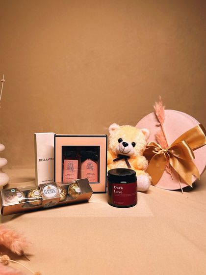 The 'Sweet Serenity' hamper is a bundle of love and comfort. It includes a cuddly teddy bear, Ferrero Rocher chocolates, a scented candle, and a perfume and lotion set.