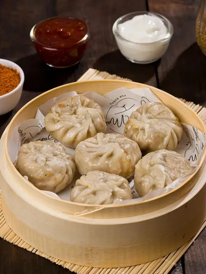 Steamed momos presented in a traditional bamboo basket, ready for a menu shoot. We style savory items with appropriate dips and garnishes to create a complete and appealing dish.