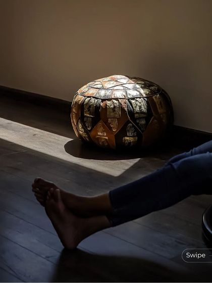 A detail shot of a leather pouf on the dark wood floor, with sunlight creating a beautiful contrast. It's these small details and textures that give a space its character.