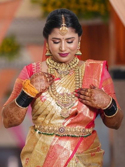 Our beautiful bride Uma, adjusting her stunning temple jewellery. She is wearing a full set with a wide choker and a grand Lakshmi pendant haram, perfect for her muhurtham look.