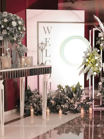 A complete welcome station with a mirrored console table, a personalized sign, and an abundance of white floral arrangements and candles.