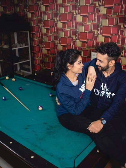 A fun and casual pre-wedding shot of a couple sharing a moment over a game of pool, showcasing their playful side.