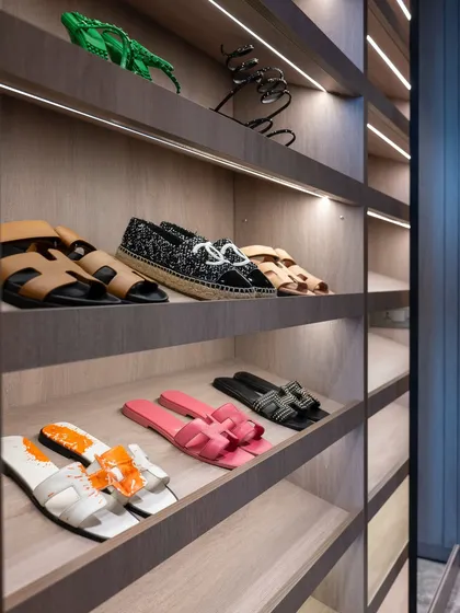A close-up of the shoe display shelves in a custom wardrobe. The soft, integrated lighting and angled shelves turn a practical storage solution into an elegant showcase for a prized collection.