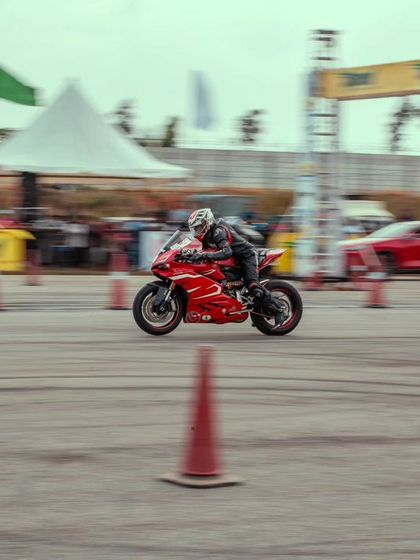 A distant shot of the red Ducati, showing its position on the track as it speeds towards the finish line. The entire venue is designed for optimal racing and viewing.