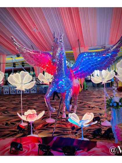 A truly magical photo booth featuring a life-sized, winged horse statue made of reflective mirrors. The statue is surrounded by glowing floral lights, creating a fantasy-like setting for pictures.