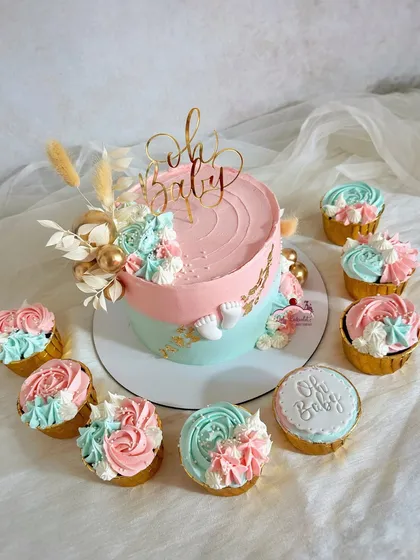 Celebrating a new arrival with this sweet 'Oh Baby' shower set. The cake features a classic pink and blue buttercream design with delicate gold leaf accents, perfectly complemented by matching rosette cupcakes.