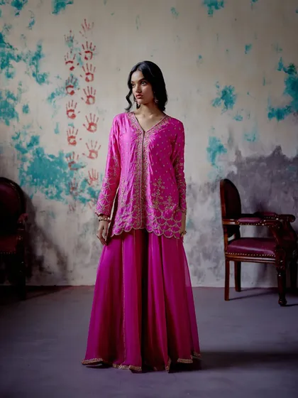 This striking fuchsia sharara set is perfect for summer soirées. The playful silhouette, vibrant colour, and delicate detailing make it a festive favourite for those who love to make a statement.