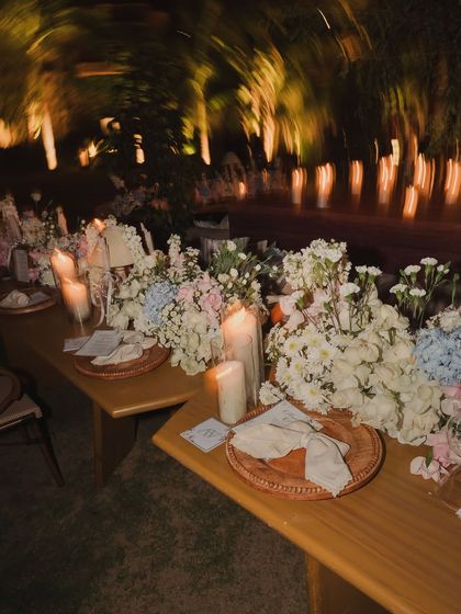 A long, beautifully set dinner table under a tunnel of lights, creating a dreamy and intimate dining experience for the Parisian-themed evening.