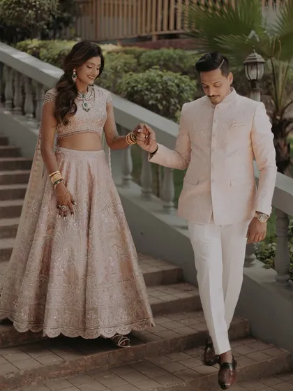 A candid shot of the couple descending a grand staircase, showcasing the flow and detail of the bride's beautiful lehenga.
