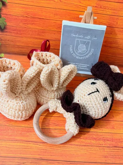 Welcome a newborn with this adorable and safe baby gift set. It features a pair of soft bunny-eared booties and a matching bunny rattle with a natural wood ring, all handmade from gentle, premium yarn.