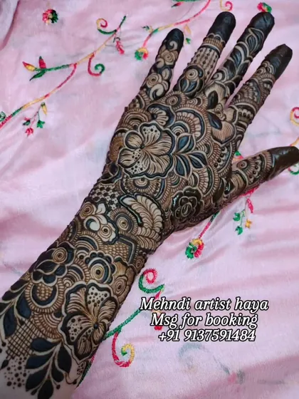 A client's hand adorned with a full-coverage floral design against a soft pink background. This is the kind of art that makes any event special.