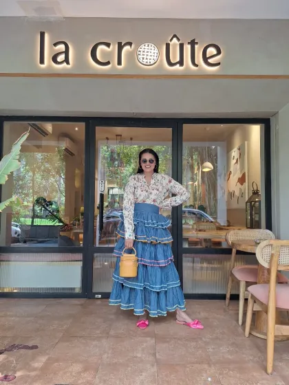 A casual day out look, elevated by accessories. The denim tiered skirt is paired with a floral shirt, but the bright pink mules and yellow woven bucket bag are what make the outfit pop.