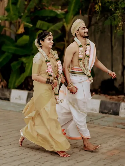 The couple walks hand-in-hand, their traditional attire and joyful expressions capturing the essence of a beautiful Kannada wedding.