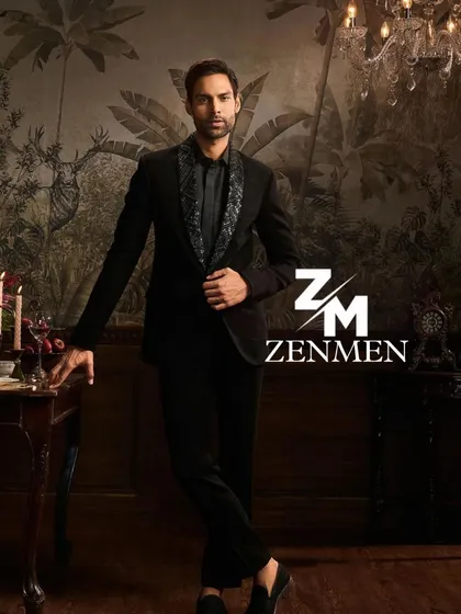 A model in a black tuxedo with a grey patterned lapel, exuding confidence in a sophisticated, moody setting.