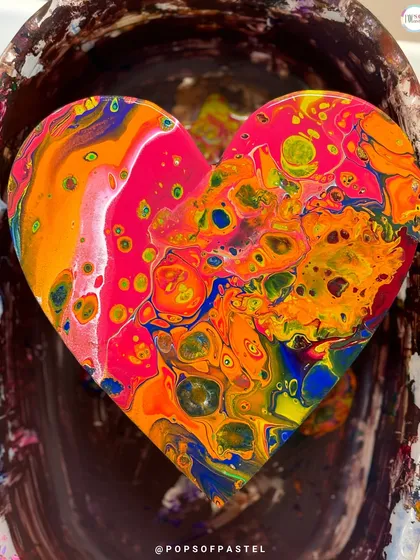 The stunning result of an acrylic pour. This vibrant heart shows the mesmerizing patterns and colors you can create in our fluid art workshops, where every piece is one of a kind.
