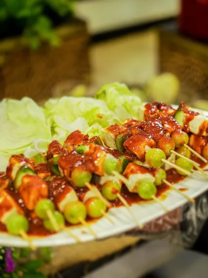 A platter of my Jain-friendly skewers, made with paneer, grapes, and bell peppers in a tangy red sauce. I can customize my menu to meet any dietary requirement.