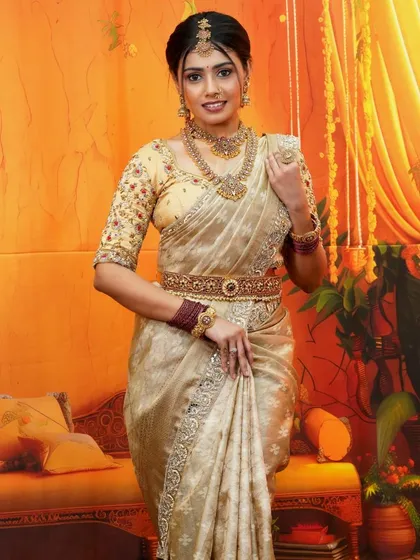 The epitome of grace, this cream and gold silk saree is for those who love understated elegance. It's a versatile piece, perfect for housewarming ceremonies, engagement parties, or as a guest at a wedding, offering a classic and sophisticated look.