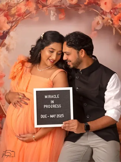 "Miracle in Progress." This couple shares their joy with a cute announcement board, creating a personal and memorable portrait.