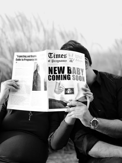 A playful black and white shot of the couple hiding behind the "New Baby Coming Soon" newspaper. It’s a fun and mysterious way to announce their news.