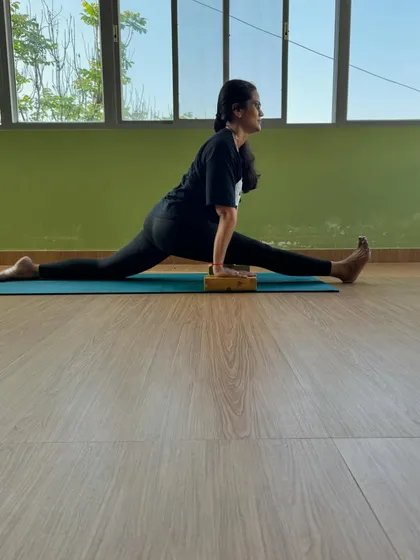 A student uses a yoga block to support her journey into Hanumanasana (front split). Props are intelligent tools, not crutches, that help the body open up safely and effectively.