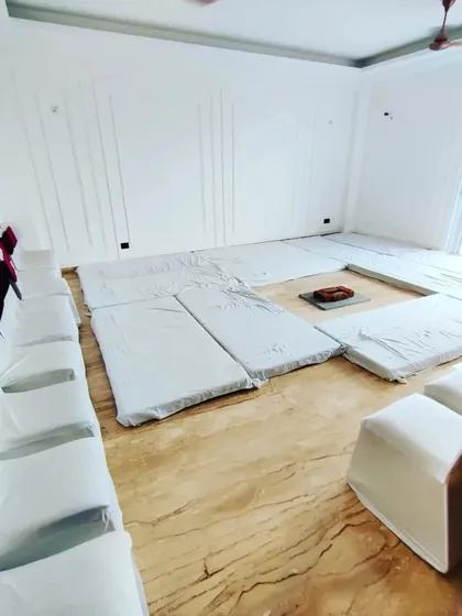 A wider view of the hawan setup, showing the floor mattresses for the ceremony and banquet chairs with covers along the wall for additional guest seating.