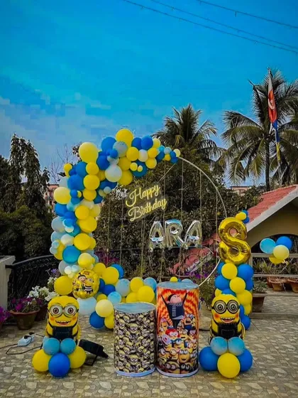 A fun Minions-themed birthday party on a terrace. The outdoor setup includes a blue and yellow balloon arch and Minion character props.
