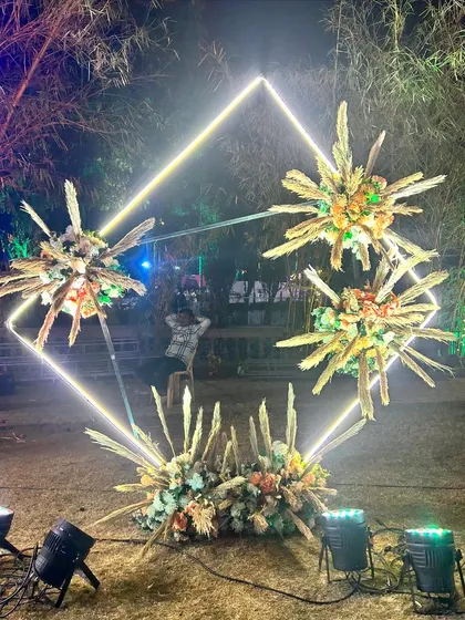A modern and abstract photo booth for the Sangeet, using a neon diamond frame and explosive floral arrangements.