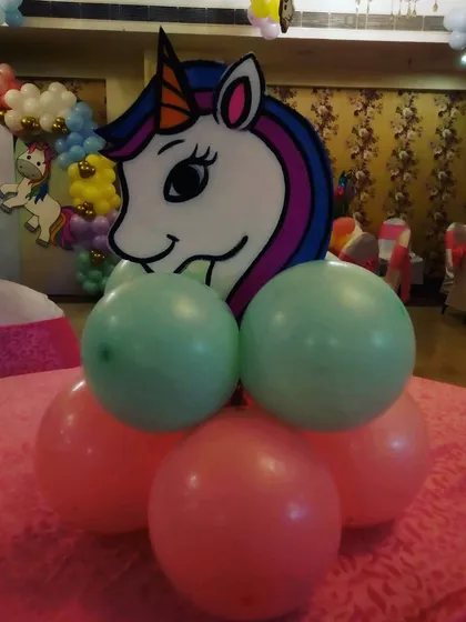 A unicorn head cutout on a pink and green balloon base, designed as a table centerpiece.