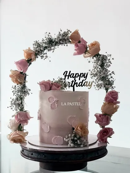 This cake is crowned with a beautiful tiara of fresh roses and baby's breath. The soft pink ombre finish and petal-like texture make it a dreamy choice for any celebration.