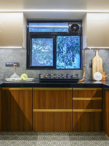 Warm wood cabinets and a dark countertop give this kitchen a cozy, rustic feel. The patterned tile floor adds a touch of vintage charm, while the large window provides ample natural light.
