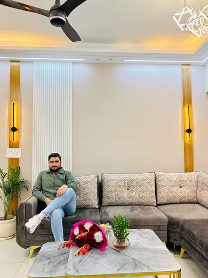 A happy moment in a newly designed living room at Nirala Estate, featuring a comfortable L-shaped sofa and elegant wall sconces.