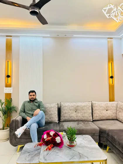 A happy moment in a newly designed living room at Nirala Estate, featuring a comfortable L-shaped sofa and elegant wall sconces.