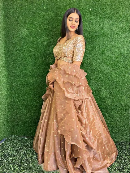 A full view of the rose gold lehenga, featuring a trendy ruffled skirt. This indo-western piece is perfect for a cocktail party or a modern sangeet.