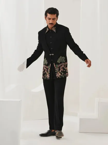A full-length view of the black floral embroidered bandhgala from the Nazaakat collection. The asymmetrical design and unique clasp make it a modern classic.