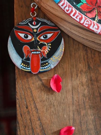 A close-up of a hand-painted Kaali face charm, one of the many found-object trims that adorn the main artwork. Each element is thoughtfully chosen and crafted to complete the story of the piece.