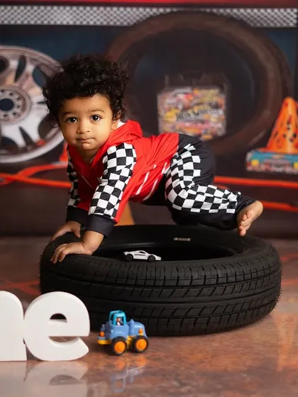 Our little racer is on the move. The setup with tires and traffic cones creates a fun and interactive environment for a first birthday shoot.
