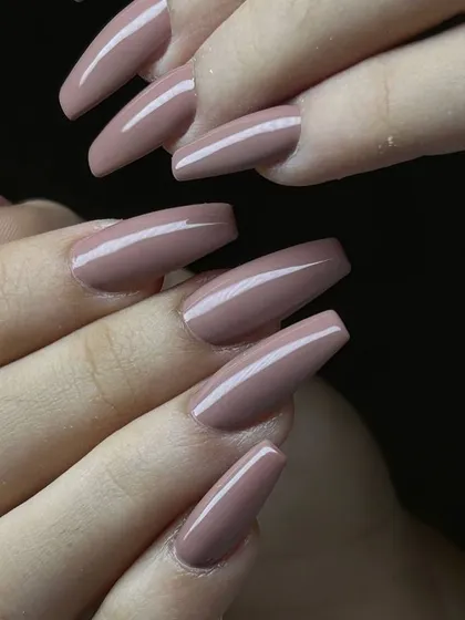A chic, mauve-nude polish on long, coffin-shaped nails. This sophisticated color and shape combination is modern and elegant.