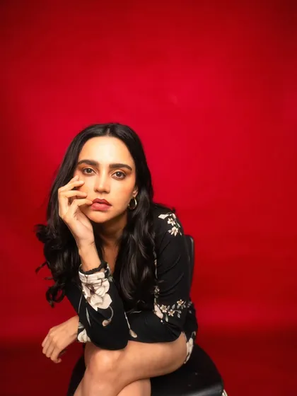 A seated portrait that feels confident and composed. The red background ensures the image is vibrant and eye-catching.