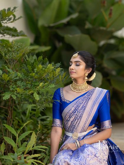 A serene portrait showing the beautiful drape of the silver and blue Kanchivaram saree, paired with a simple royal blue blouse.