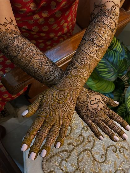 This full bridal design combines floral elements with traditional Indian patterns. The groom's initials are beautifully integrated into the design on the palm.