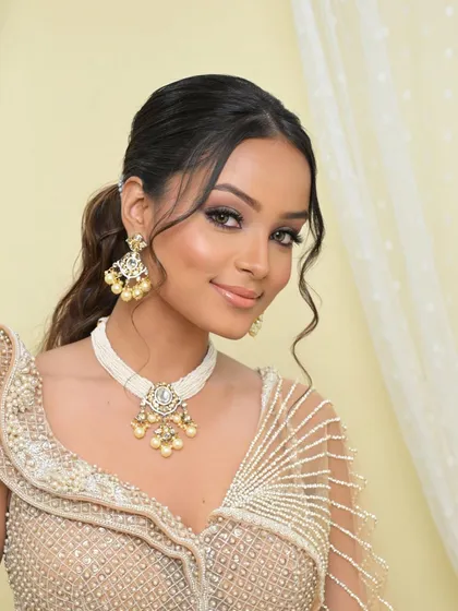 A smiling portrait that captures the fresh and modern feel of this look. The messy ponytail and glowing skin create a vibe that is effortlessly chic.