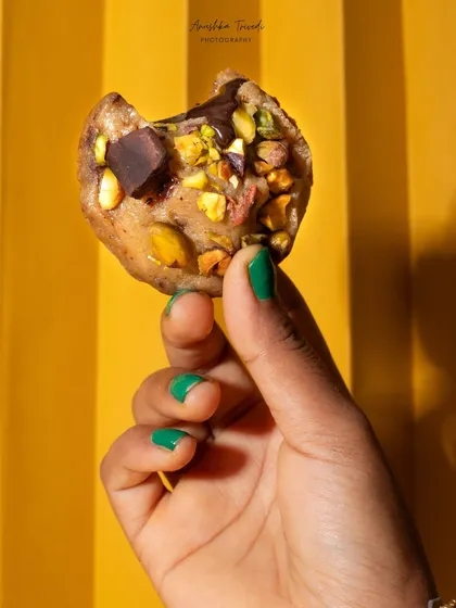 A hand holding up a half-eaten cookie against a bright yellow background. This playful and casual shot is perfect for social media, feeling authentic and relatable.