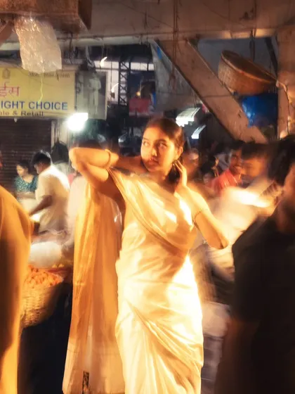 Using a slow shutter speed to create motion blur, the model stands still while the market crowd flows around her. This technique separates the subject from the chaos.