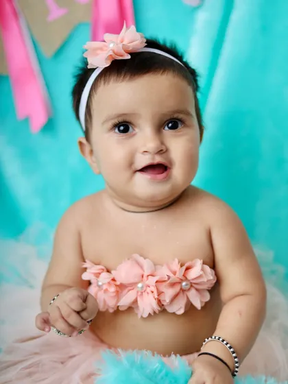 A sweet and simple baby portrait. The floral top and pink tutu pop against the bright turquoise background, highlighting her happy expression.