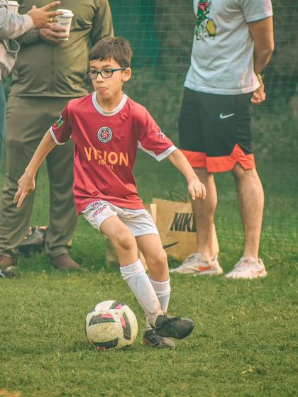 A young player with glasses shows intense focus as he controls the ball during the Pride Cup.