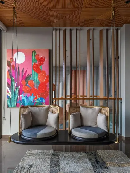 A modern swing with comfortable cushions hangs in the living area, offering a playful seating option with a view of the vibrant wall art.