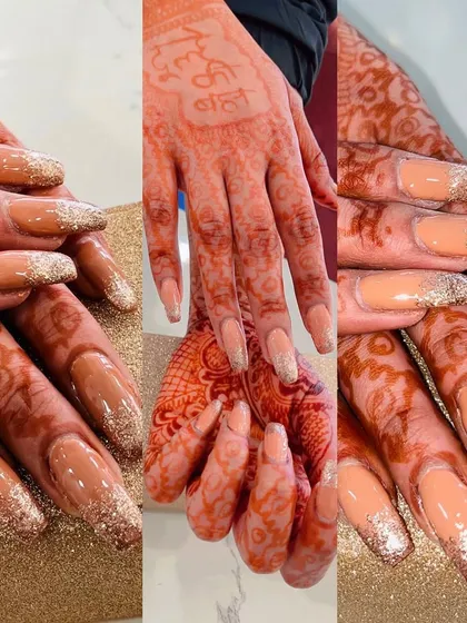 These bridal nail extensions were designed to complement the client's beautiful henna. The long, square-shaped nails feature a nude base with a sparkling gold glitter fade from the tips, creating a glamorous and festive look.