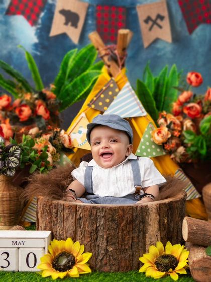 A happy camper! This little one is all smiles in his rustic log seat, part of a fun and adventurous camping-themed session.