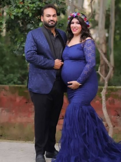 A full-length view of the blue lace mermaid gown with a tulle train. This dress combines the elegance of lace with the drama of a full train, making it a wonderful option for a formal maternity shoot.